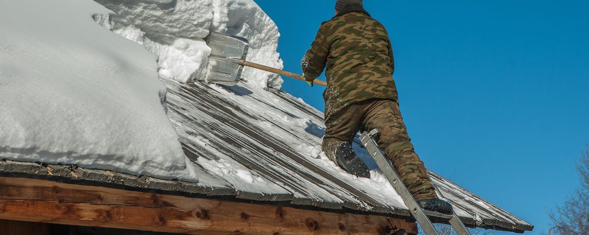 man removing snow off roof