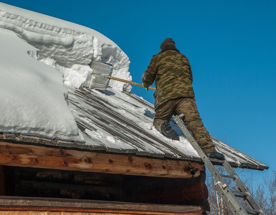 man removing snow off roof